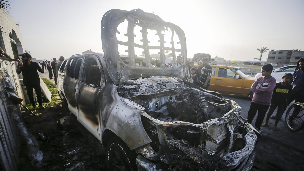 La gente observa el automóvil destruido de la ONG World Central Kitchen (WCK) a lo largo de la carretera Al Rashid, entre Deir Al Balah y Khan Younis en el sur de Gaza, el martes 2 de abril de 2024.
