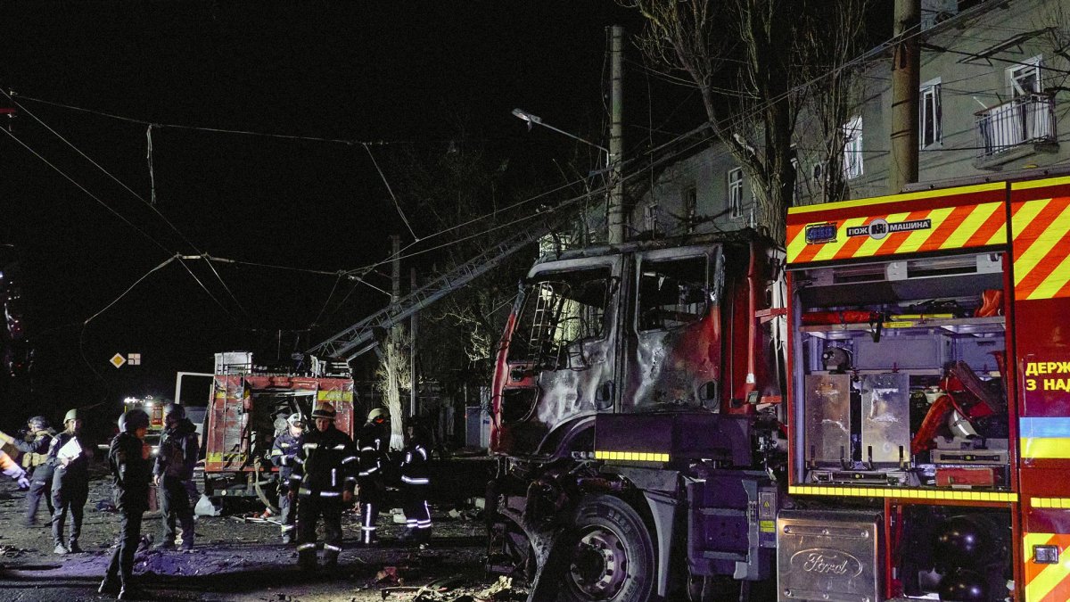 Rescatistas ucranianos trabajan cerca de su vehículo dañado en la escena de un ataque nocturno ruso con drones contra un edificio residencial en Járkov.