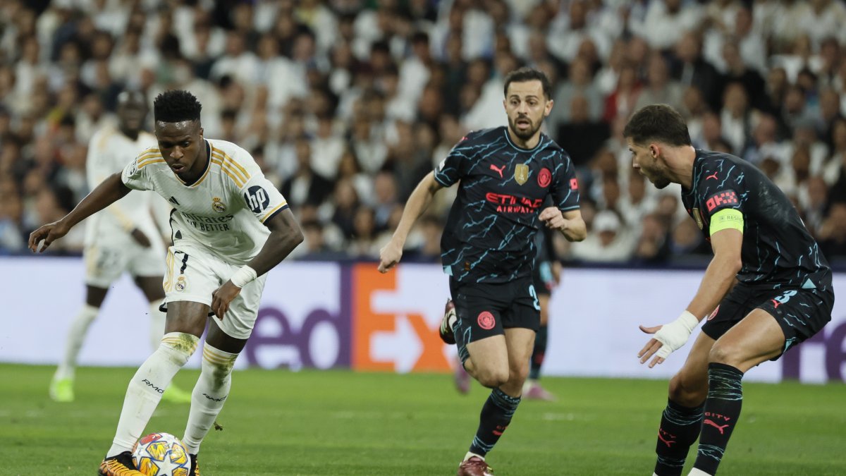 El delantero brasileño del Real Madrid Vinicius Jr. (i) se escapa con el balón de los jugadores de Manchester City