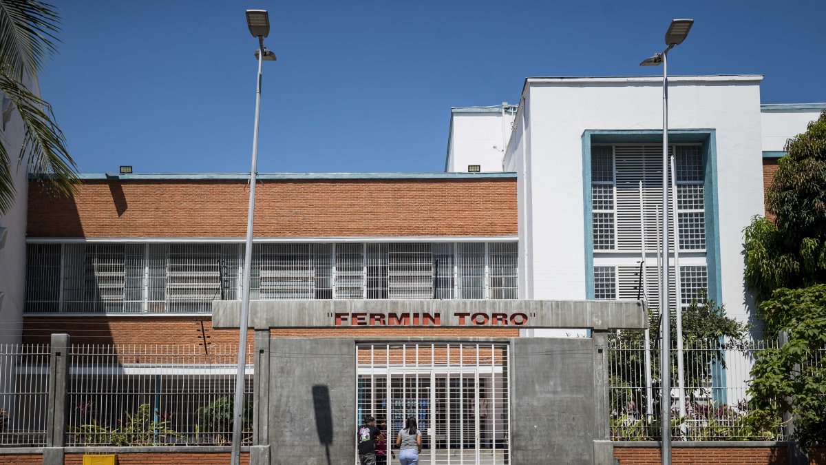 Personas aguardan en la puerta de una unidad educativa pública de una zona popular, en Caracas (Venezuela).