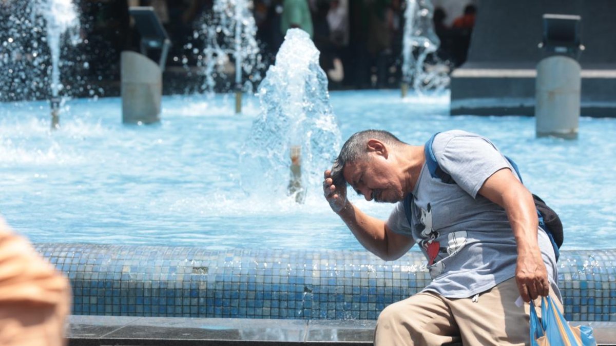 Un ciudadano se moja en una pileta en el centro de Guayaquil.