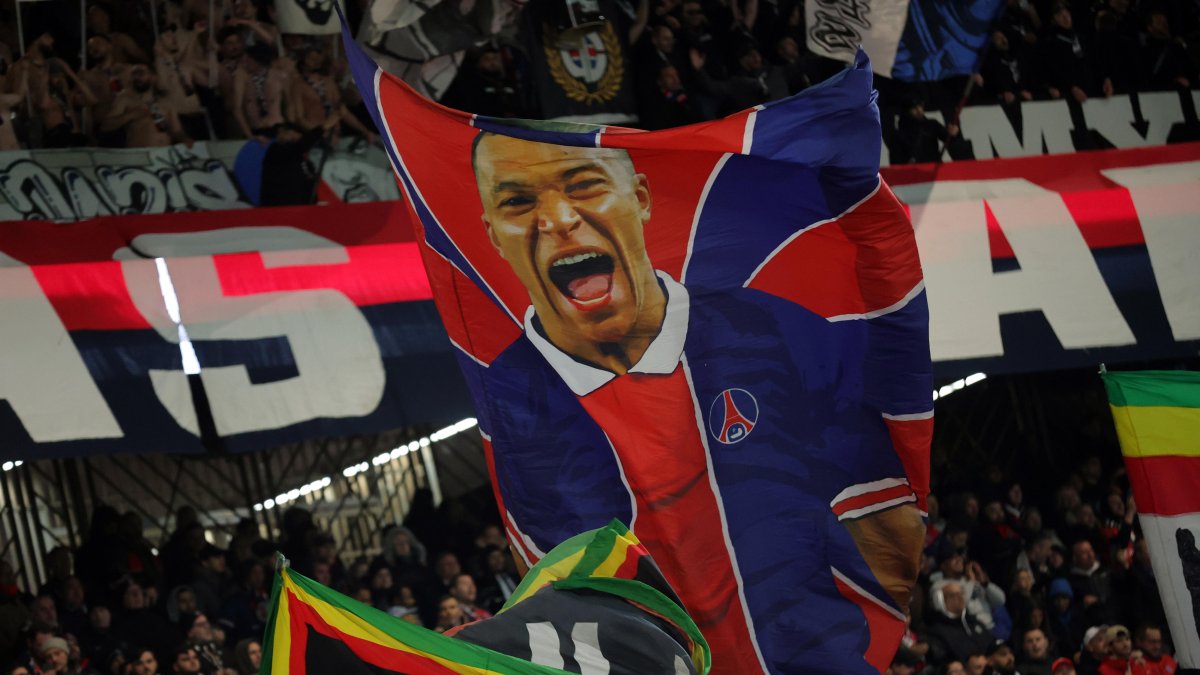 Los partidarios de París Saint Germain ondean una bandera que representa al jugador Kylian Mbappé.