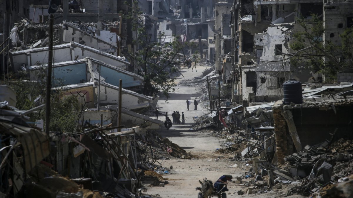 Varios palestinos caminan entre edificios destrozados en Jan Yunis tras un ataque israelí.