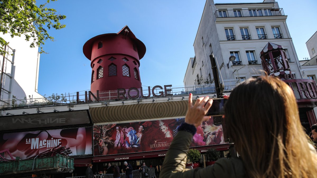 La gente toma fotos de la fachada del Moulin Rouge sin sus alas en París. Durante la noche del 24 al 25 de abril de 2024, las aspas del Moulin Rouge se derrumbaron sin causar víctimas.