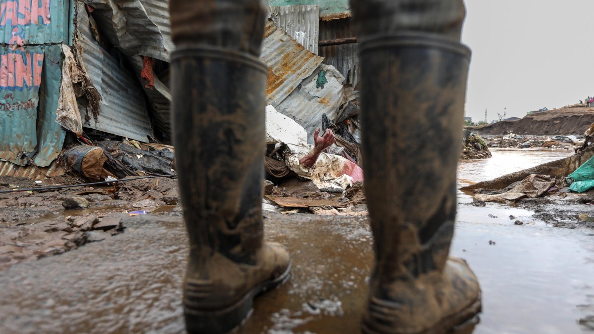 La gente se reúne alrededor del cuerpo de un hombre que fue descubierto cuando el río Gitathuru retrocedió tres días después de que las fuertes lluvias se desbordaran.