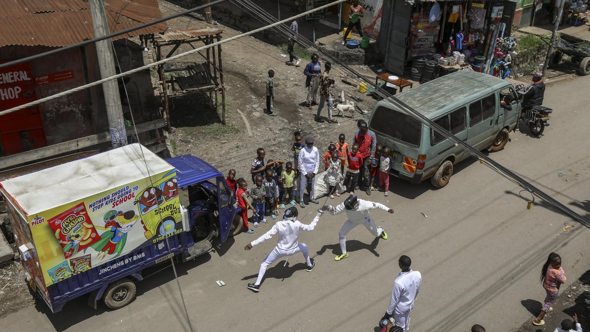 El esgrimista profesional keniano Isaac Mburu Wanyoike (d) entrena con miembros adolescentes del club Tsavora Fencing Mtaani en las calles del barrio marginal de Huruma en Mathare.