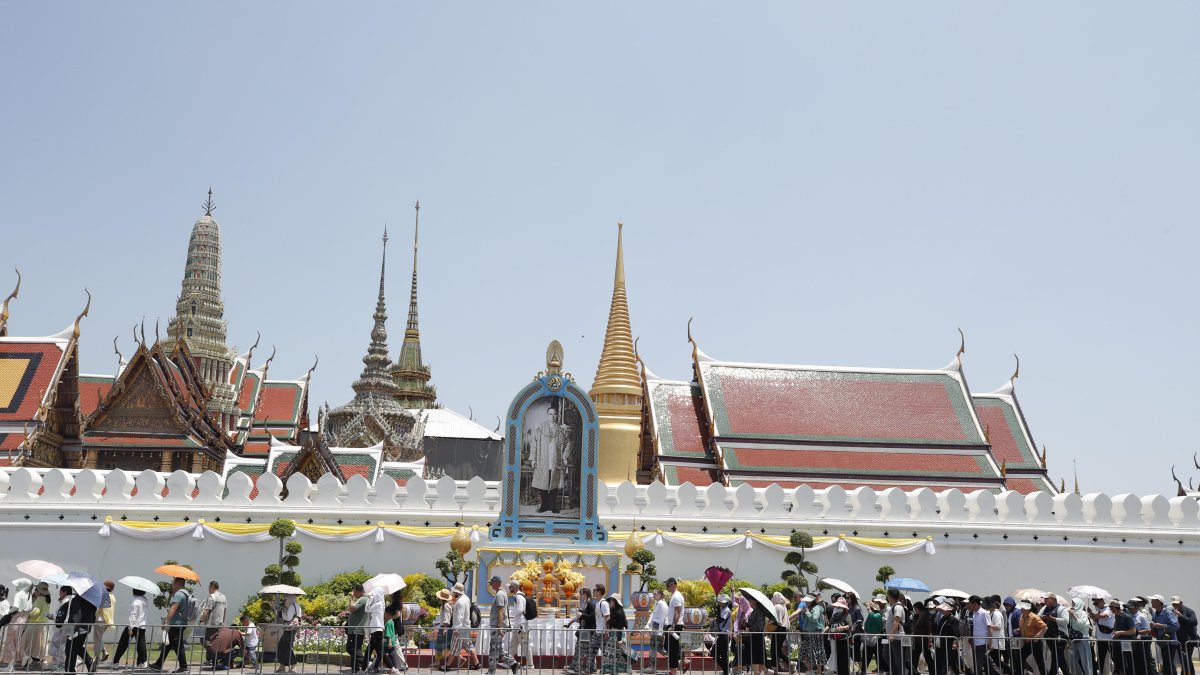 Un grupo de turistas se protege del sol en el Gran Palacio de Bangkok en medio de la fuerte ola de calor que golpea Tailandia y el sureste de Asia.