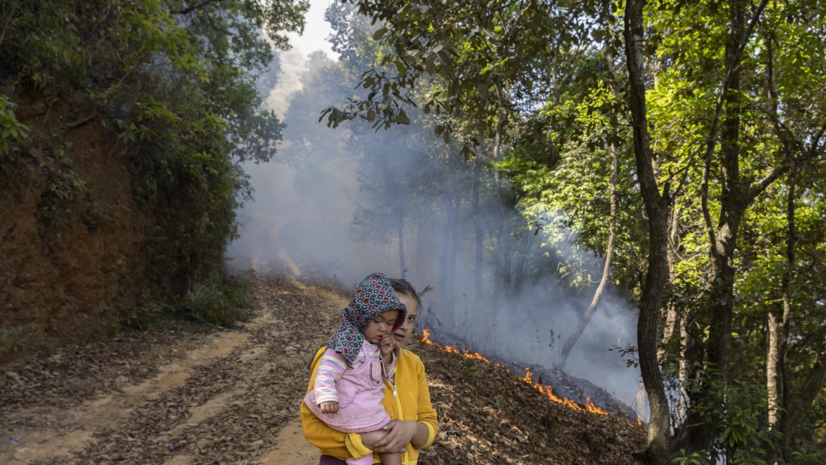 Una mujer local y un niño observan el incendio forestal cerca de la aldea de Godawari, en las afueras de Katmandú, Nepal, el 2 de mayo de 2024.