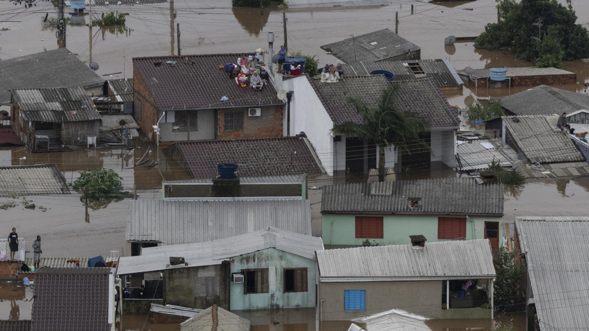 Personas esperan ayuda en el techo de su casa durante una operación de rescate del ejército brasileño junto con los bomberos en Canoas (Brasil).