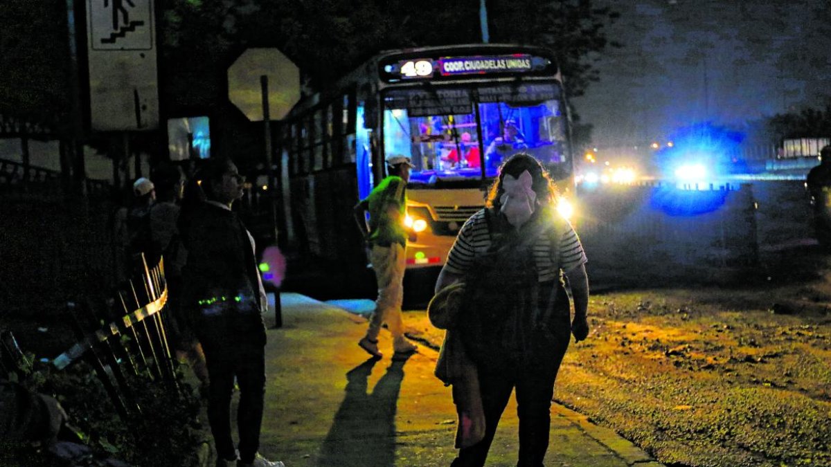 Los pasajeros esperan los buses en una oscuridad tenebrosa.