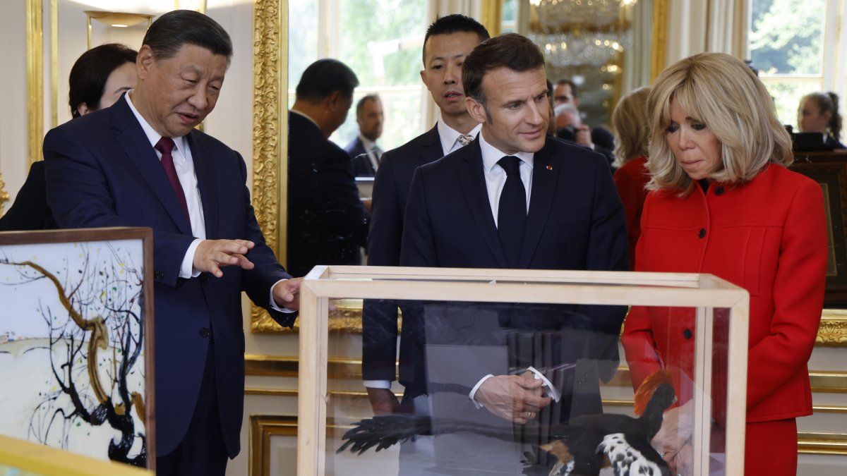El presidente Xi Jinping (i) y Emmanuel Macron, miran los regalos durante el intercambio de obsequios entre las naciones, en el Palacio Presidencial del Elíseo en París.
