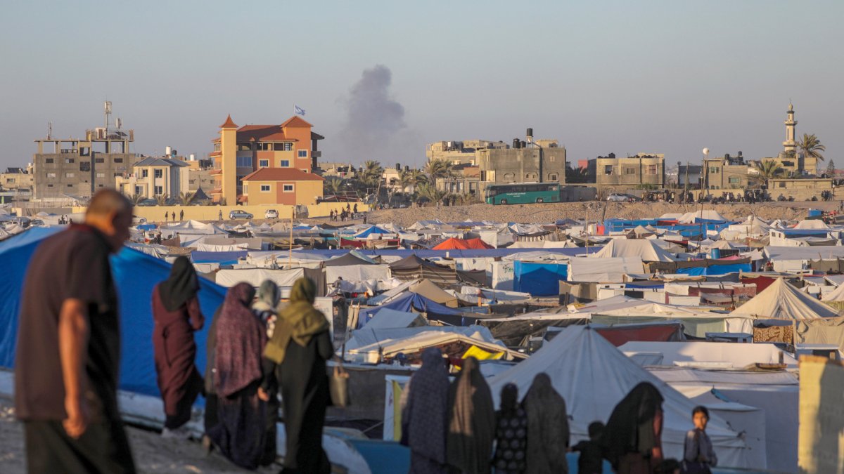 Palestinos desplazados internos en un campamento miran el humo que se eleva al fondo después de un ataque aéreo israelí, en Rafah, en el sur de la Franja de Gaza, el 7 de mayo de 2024.