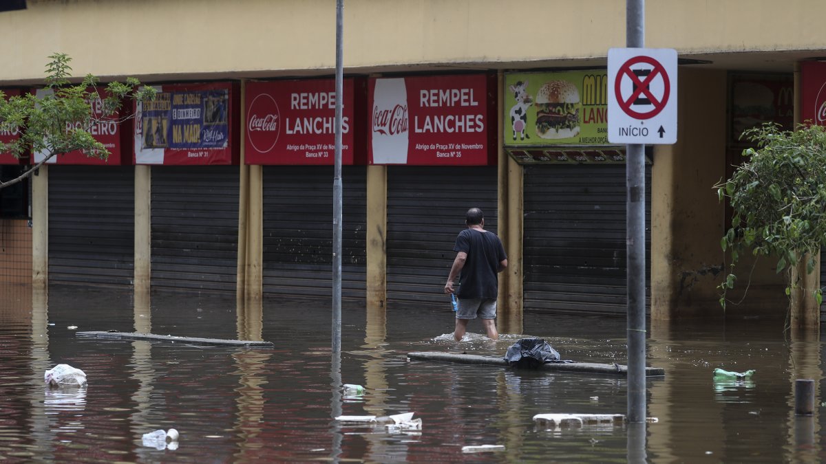 Un hombre camina en una calle inundada de agua y basura en un centro comercial este lunes, en Porto Alegre (Brasil).