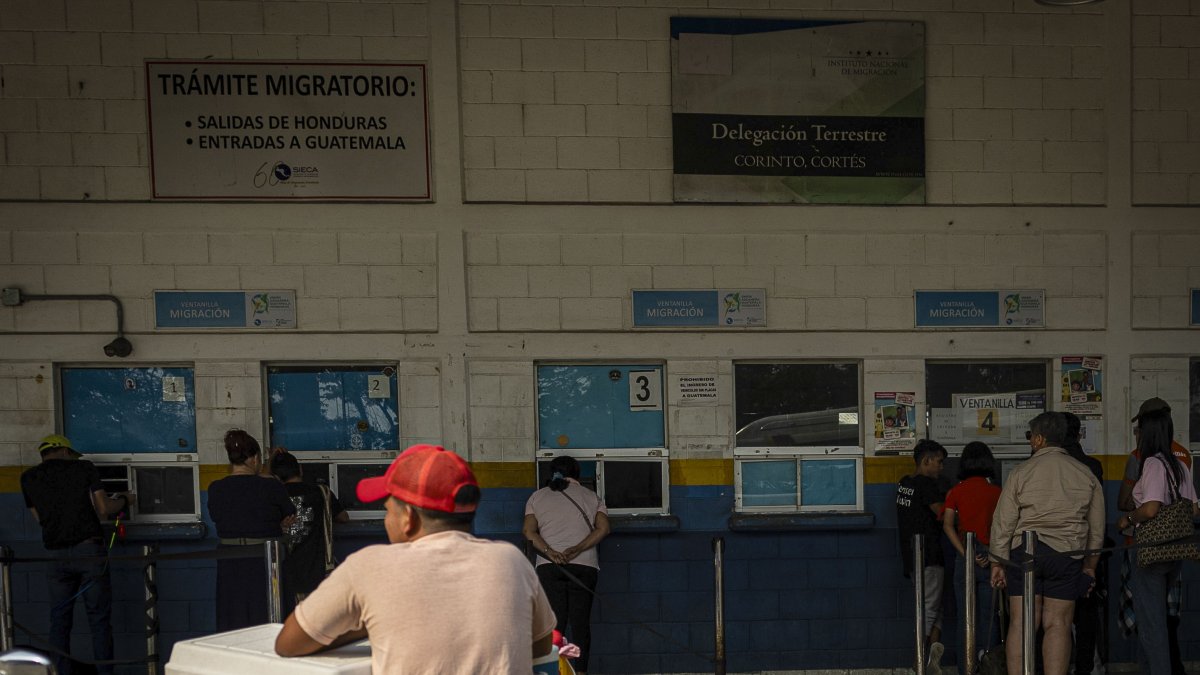 Decenas de hondureños pasan por la aduana de su país para ingresar a Guatemala en el puesto fronterizo de El Corinto.