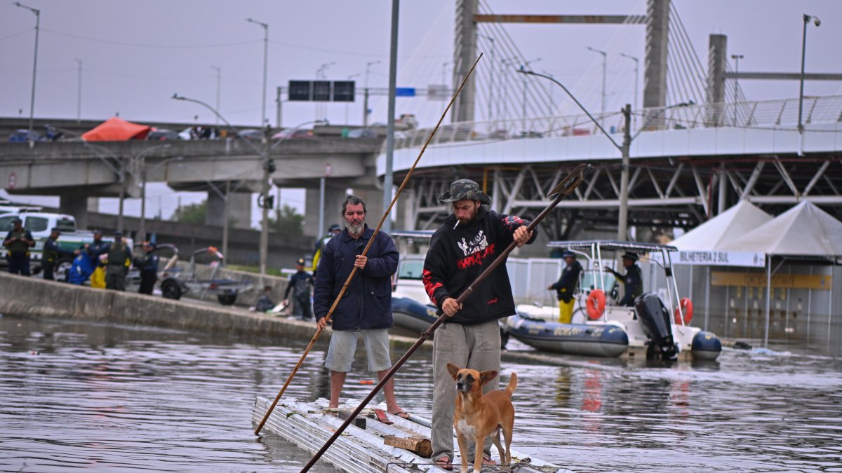Dos hombres utilizan unas tejas para navegar en una zona inundada el 16 de mayo de 2024, en el municipio de Canoas, estado de Rio Grande do Sul (Brasil).