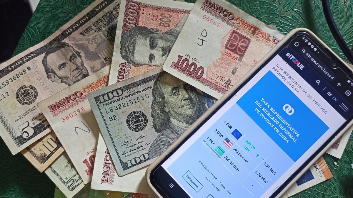 Se muestran billetes junto a un celular con la aplicación del diario digital independiente El Toque,