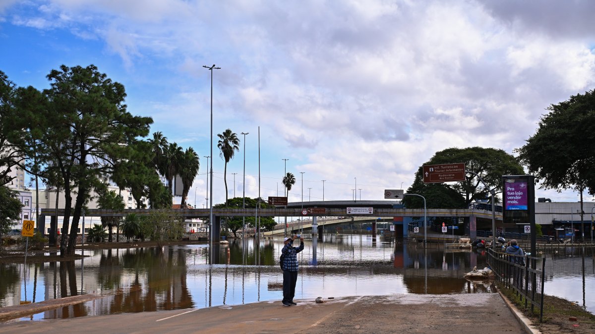 Un hombre usa su celular para tomar fotografías de una zona afectada por las inundaciones, el 18 de mayo de 2024, en el centro histórico de Porto Alegre, estado de Rio Grande do Sul (Brasil).