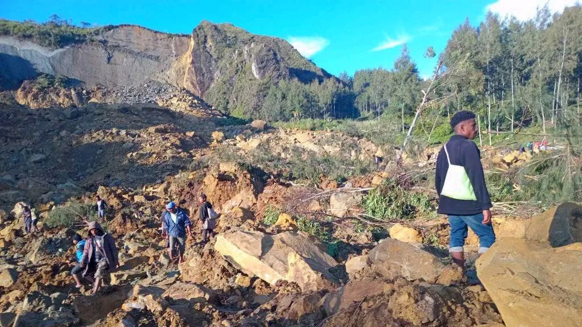 La gente camina con sus pertenencias en la zona donde un deslizamiento de tierra azotó la aldea de Kaokalam, provincia de Enga, Papúa Nueva Guinea, el 24 de mayo de 2024.