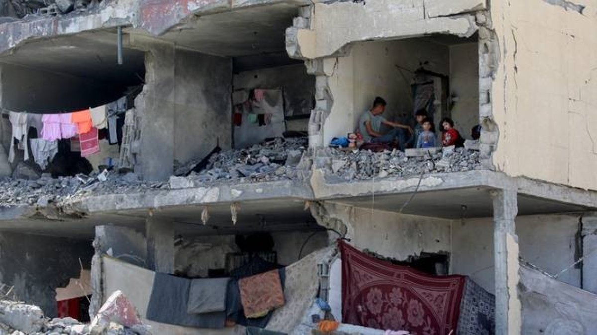 Un hombre palestino y sus hijos en una habitación destruida tras un bombardeo israelí en Rafah