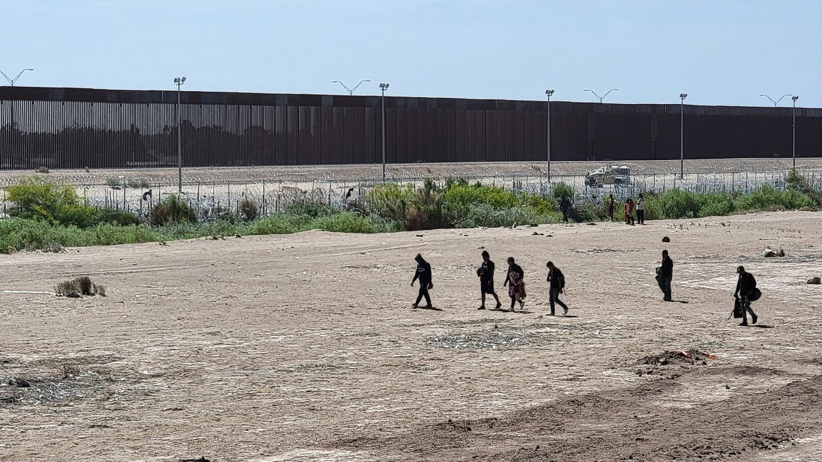 Ciudad Juárez. Varios migrantes caminan cerca de la línea divisoria entre Estados Unidos y México.