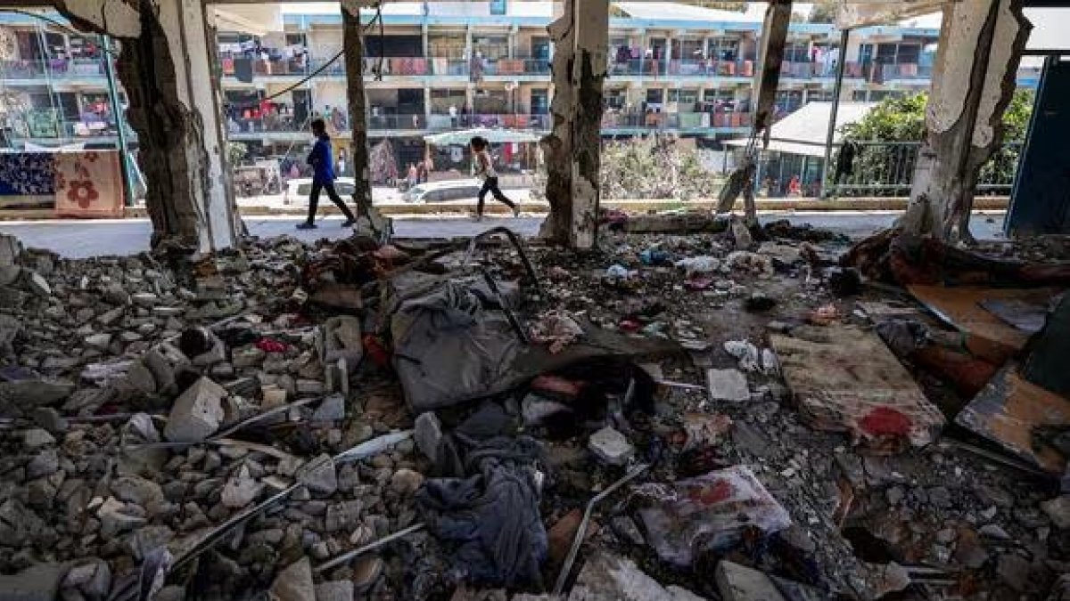 Los niños pasan junto a un aula destruida.