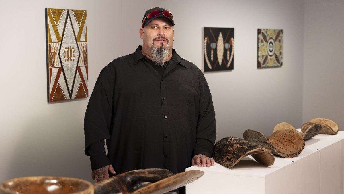 Timothy, de los Wiradjuri, posa junto a varias piezas de arte.