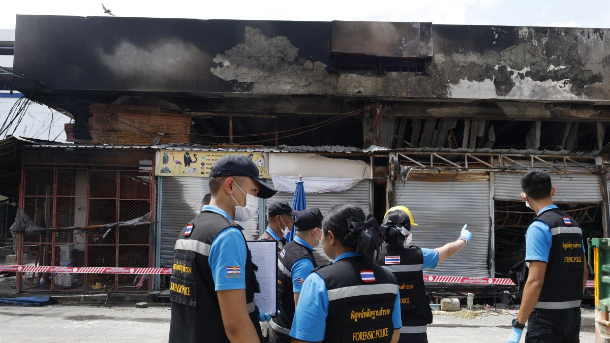Agentes de la policía forense tailandesa inspeccionan el área de un incendio en una tienda de mascotas y animales exóticos en el mercado Chatuchak en Bangkok.