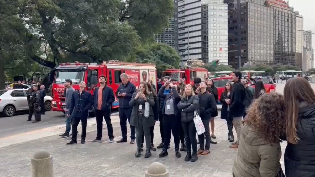 Decenas de personas observan los momentos en el que el 'influencer' polaco Marcin Banot, trepó 25 pisos de un rascacielos de 125 metros de alto en el centro de Buenos Aires.