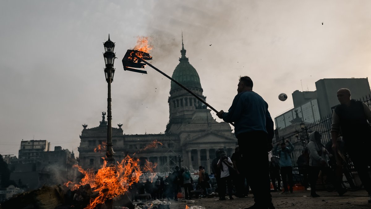 Un hombre quema una caja durante enfrentamientos entre la policía y personas que protestan a las afueras del Senado.