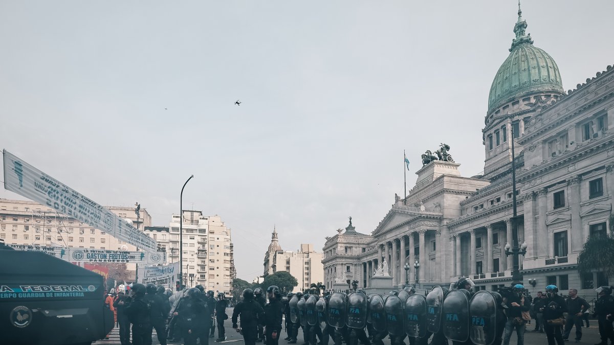 Policías intentan proteger de los manifestantes el Senado argentino, donde se aprobó la esperada ley Bases.