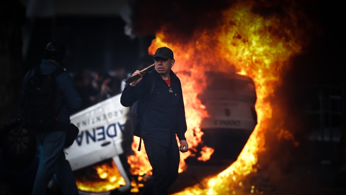 Un hombre es visto caminar frente a una carro en llamas en una protesta a las afueras del senado durante un debate este miércoles, en Buenos Aires (Argentina).