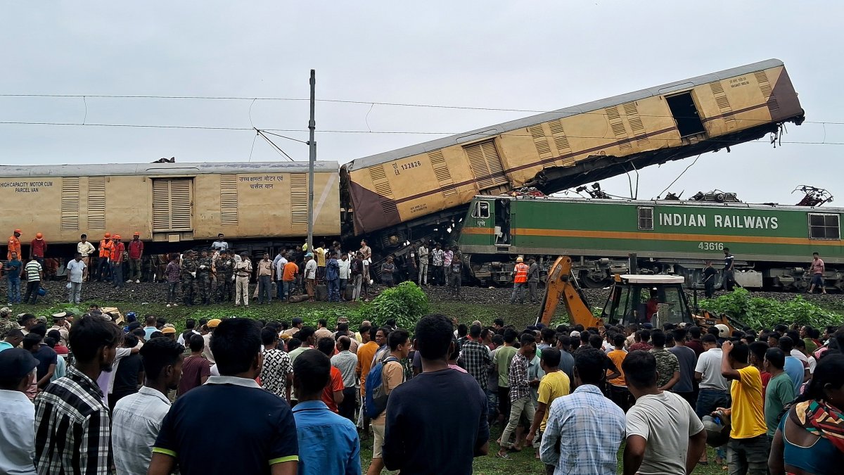 Curiosos observan cómo los rescatistas de la Fuerza Nacional de Respuesta a Desastres (NDRF) trabajan en el lugar de una colisión de trenes, cerca de la estación Rangapani, el 17 de junio de 2024.