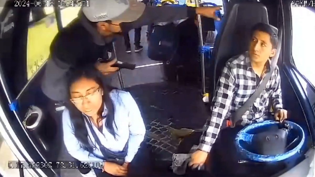 Uno de los tres delincuentes que se subieron al bus amenaza al conductor y a la pasajera que estaba junto a él