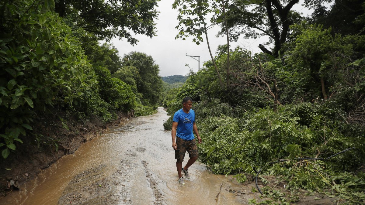 Un hombre camina por un sendero inundado debido a fuertes lluvias, el 21 de junio del 2024, en Soyapango.