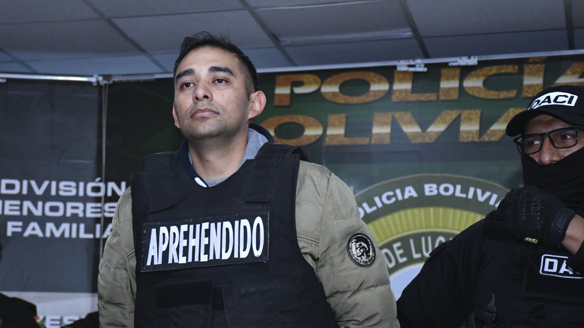 Un agente de la Dirección de Análisis Criminal e Inteligencia (DACI) escolta al capitán de infantería Miguel Burgos, durante su presentación luego de su arresto en La Paz (Bolivia).