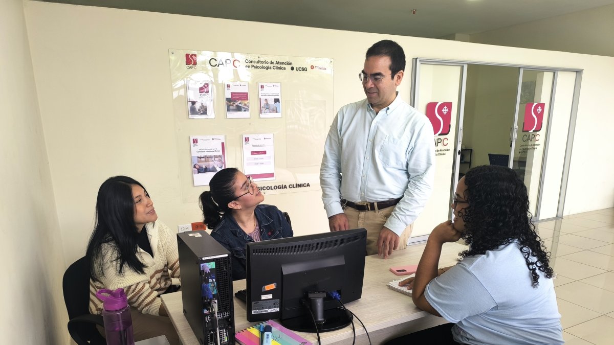 Rodolfo Rojas, director del centro de atención psicológica de la UCSG, junto a estudiantes de pregrado que colaboran en la entidad.