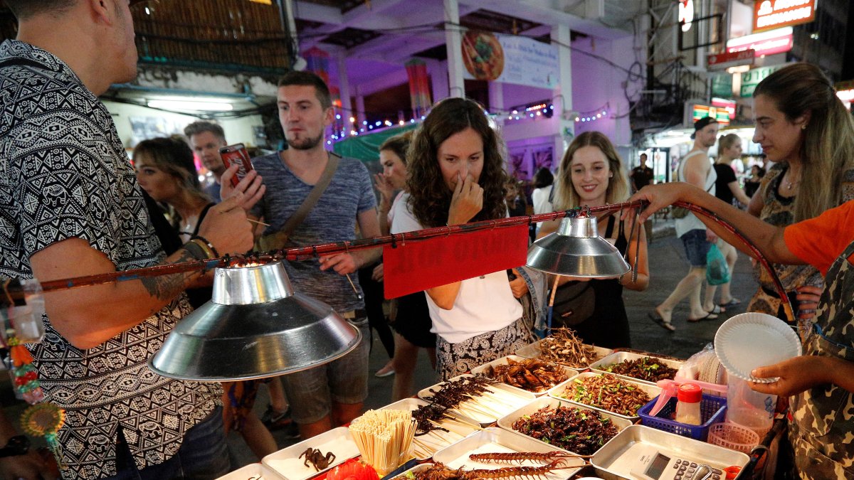 Un grupo de turistas en Bangkok comprando insectos comestibles como grillos, saltamontes o gusanos de seda.