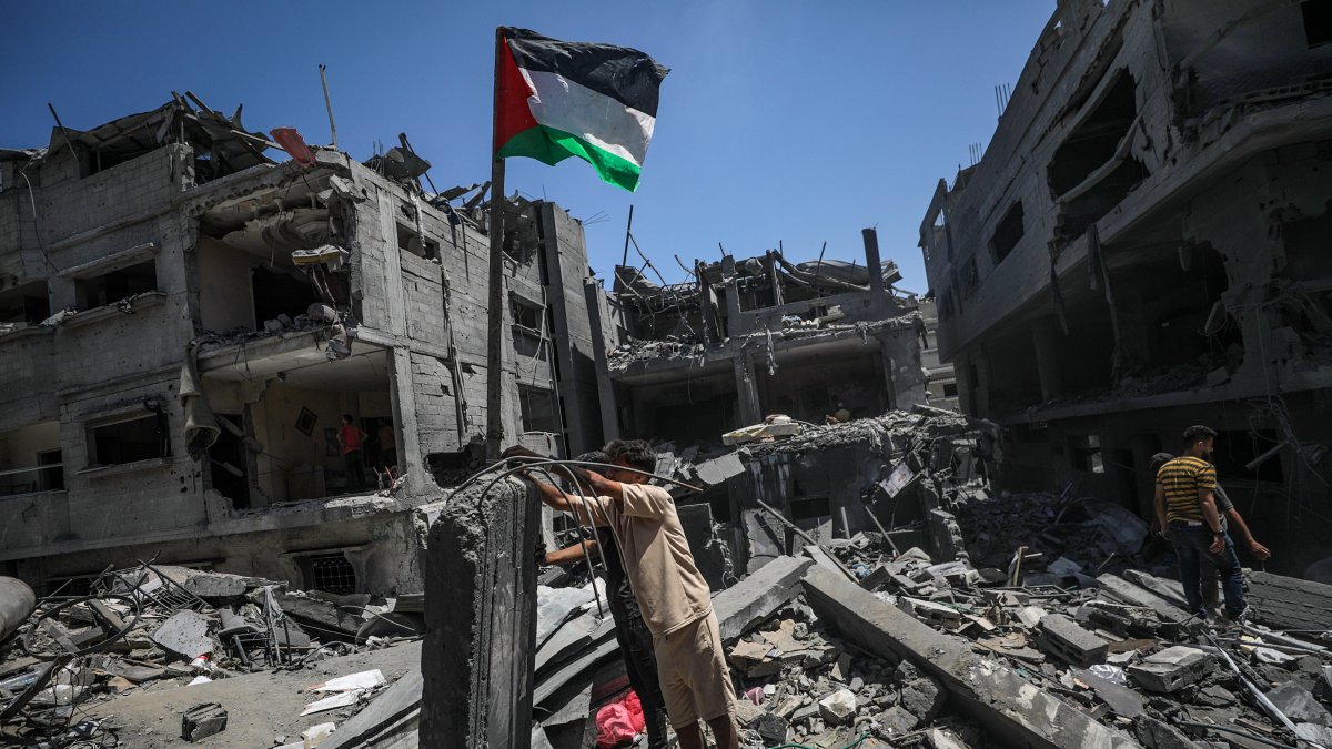 Gaza. Un hombre coloca una bandera palestina en medio de edificios destruidos tras un ataque aéreo israelí.