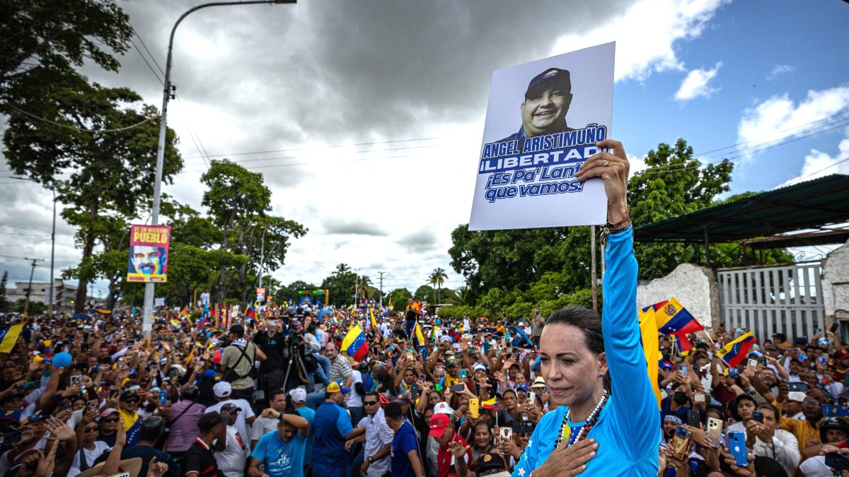 La líder antichavista María Corina Machado sostiene la imagen de Angel Aristimuño, presidente del partido Un Nuevo Tiempo en Monagas, durante una caravana.