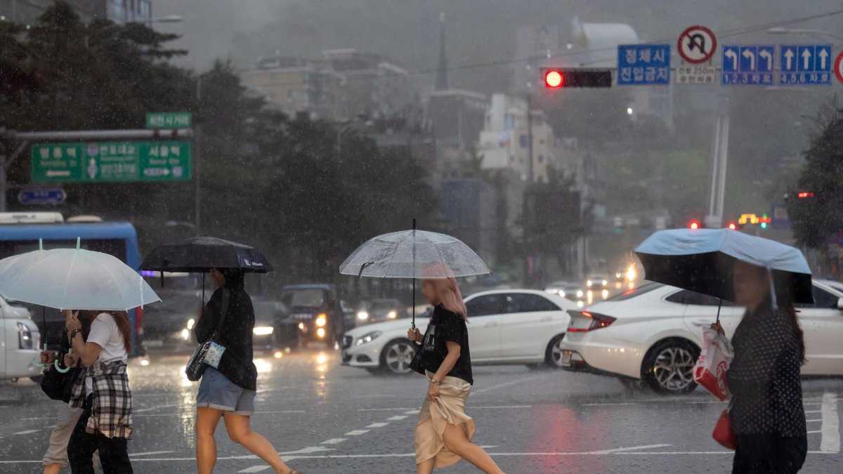 Varias personas cruzan una calle en Seúl (Corea del Sur), en medio de la lluvia debido a la influencia del tifón Gaemi que avanza hacia la Península de Corea.