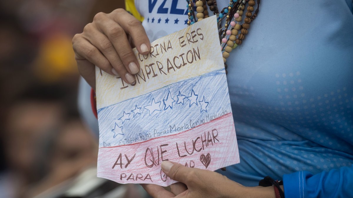 La líder opositora venezolana María Corina Machado sostiene un cartel en un acto de campaña en apoyo al candidato a la presidencia de Venezuela, Edmundo González.