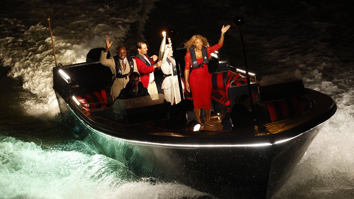 La antorcha olímpica baja por el Sena en un barco con (de izquierda a derecha) Carl Lewis, Rafael Nadal, Nadia Comaneci y Serena Williams durante la ceremonia de apertura de los Juegos Olímpicos de París 2024, en París, Francia, el 26 de julio de 2024.
