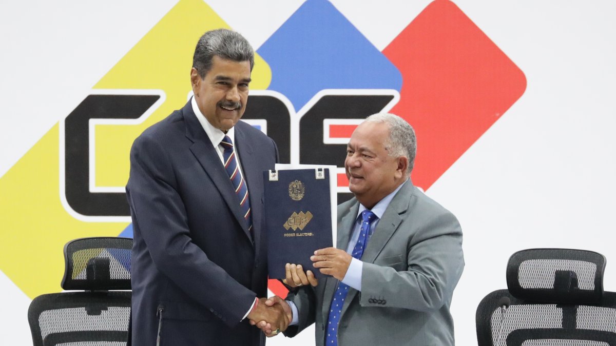 El presidente de Venezuela, Nicolás Maduro (i), y el presidente de Consejo Nacional Electoral (CNE), Elvis Amoroso, sostienen el acta de juramentación