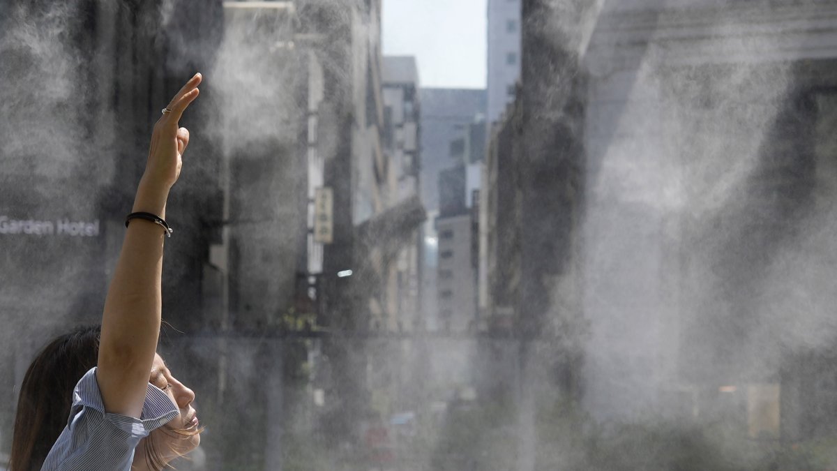 Tokio. Una mujer se refresca en un chorro de agua en un día caluroso.