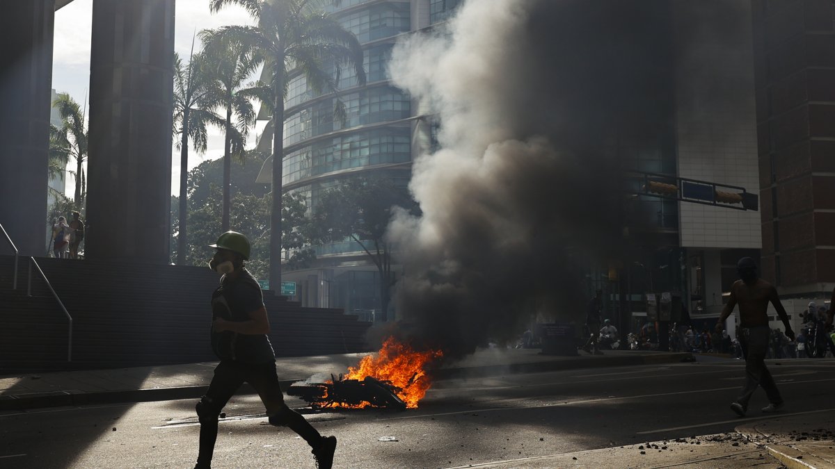 Un manifestante corre durante enfrentamientos entre opositores y miembros de la Guardia Nacional Bolivariana (GNB).