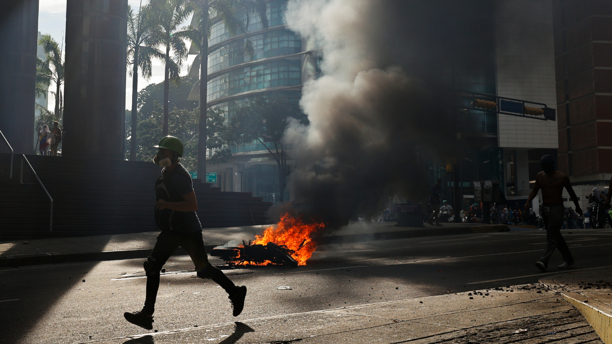 Un manifes.tante corre durante enfrentamientos entre opositores y miembros de la Guardia Nacional Bolivariana (GNB)