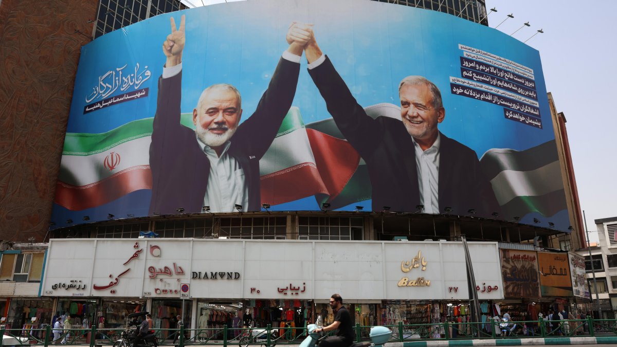 Los iraníes pasan frente a una valla publicitaria que representa al presidente iraní Massed Pezeshkian.