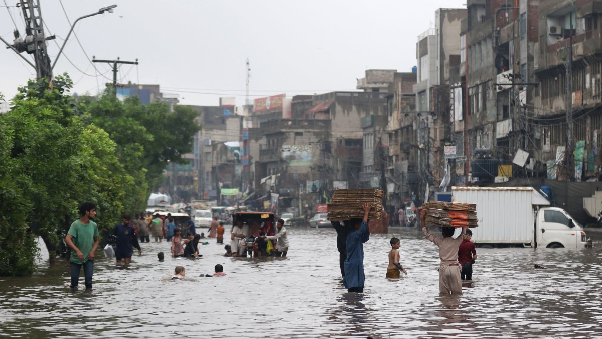 Personas y vehículos avanzan por una calle inundada después de fuertes lluvias en Lahore, Pakistán, el 1 de agosto de 2024.