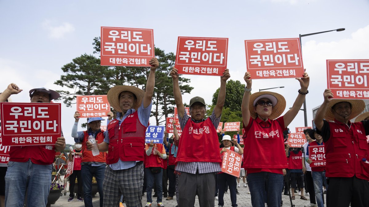 Los miembros de la Asociación Coreana de Carne de Perro sostienen pancartas que dicen 