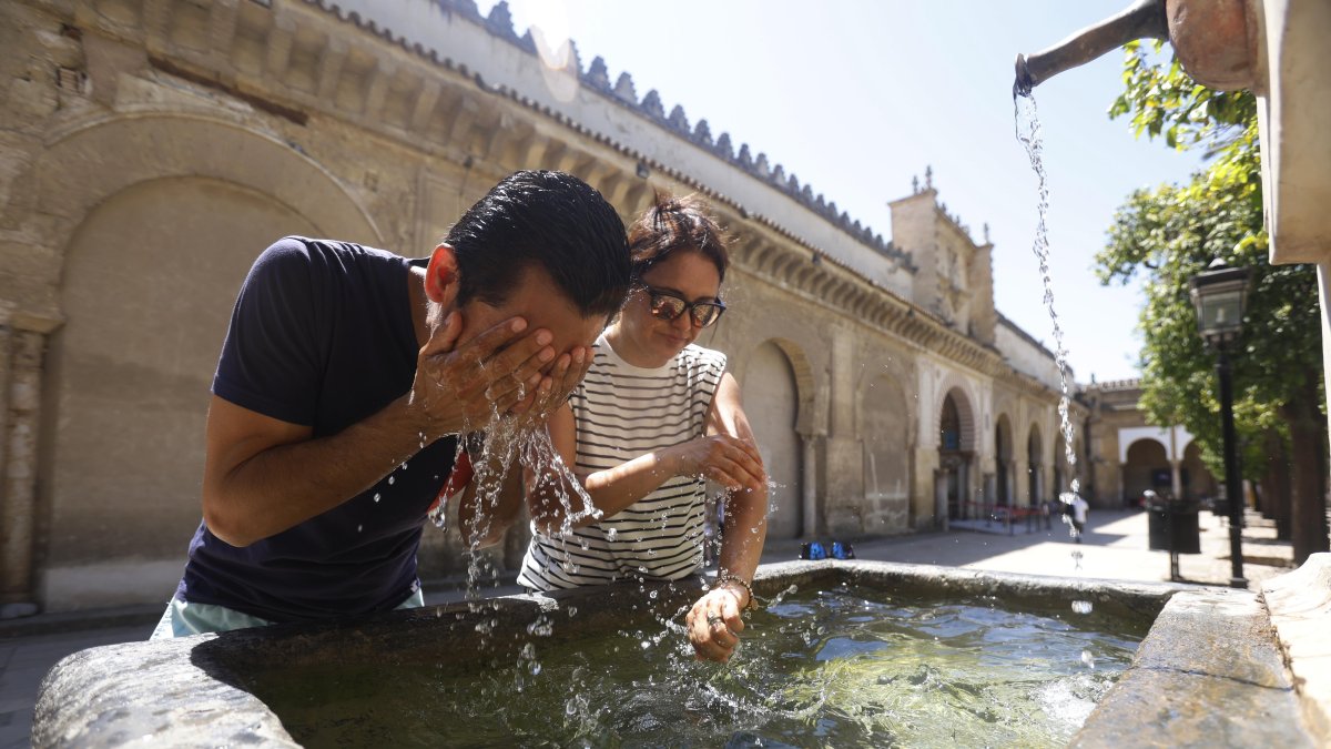 Unos turistas se refrescan en una fuente del Patio de los Naranjos de la Mezquita Catedral de Córdoba (España).